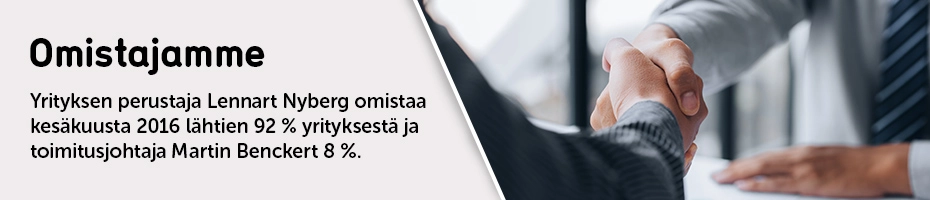 Kaksi pukuihin pukeutunutta henkilöä kättelee pöydän yli, mikä symboloi liiketoimintasopimusta tai yhteistyötä.