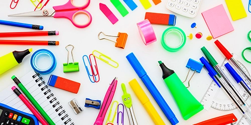 Un ensemble de fournitures de bureau et scolaires colorées, telles que des stylos, des ciseaux, des trombones, du ruban adhésif, des surligneurs et des carnets, disposées sur une table blanche. Un ensemble de fournitures de bureau et scolaires colorées, telles que des stylos, des ciseaux, des trombones, du ruban adhésif, des surligneurs et des carnets, disposées sur une table blanche.