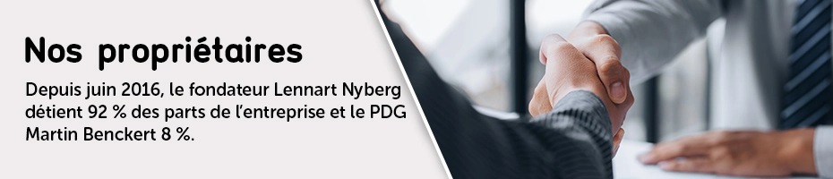 Deux personnes en costume se serrent la main au-dessus d’un bureau, symbole d’un accord commercial ou d’un partenariat.