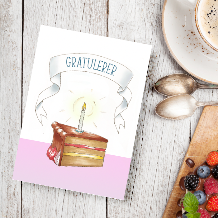 Gratulasjonskort med en kake på, liggende på et kaffebord.