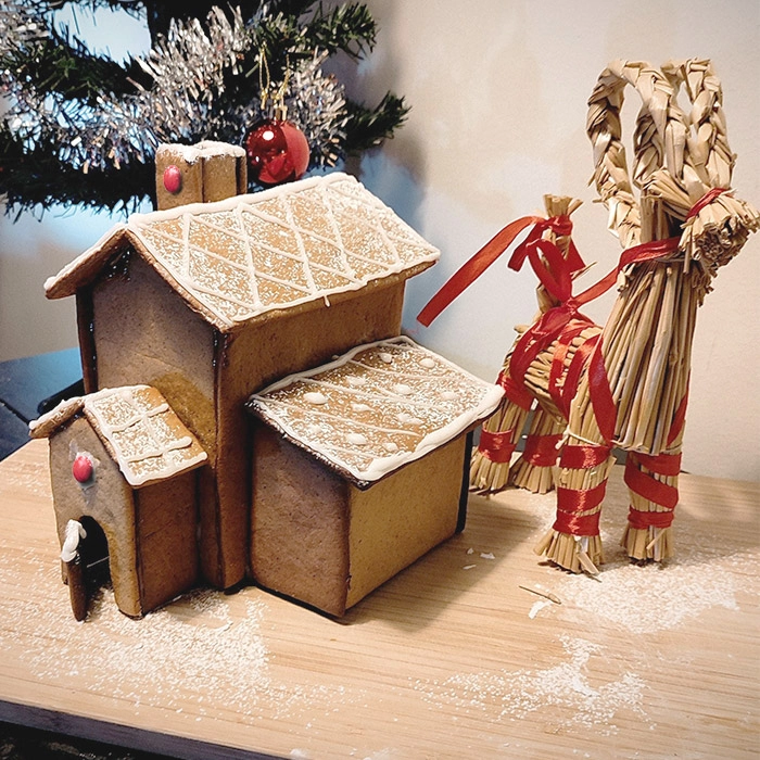 Ett pepparkakshus på ett bord bredvid en julbock
