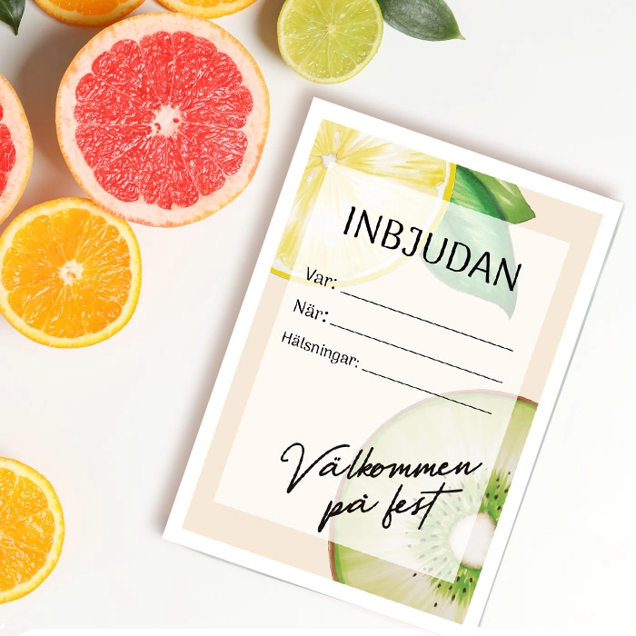 Inbjudningskort med fruktdesign ligger på ett bord bredvid skivade citrusfrukter