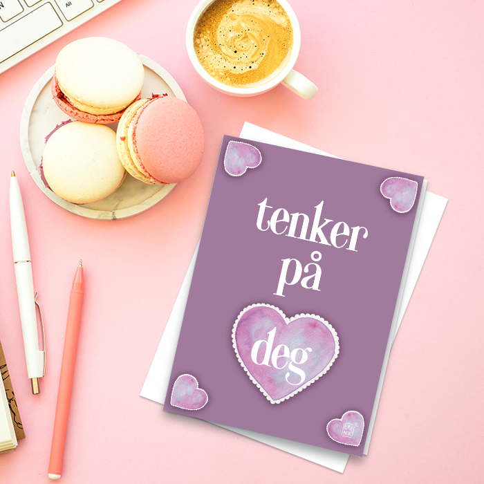 Lilla kort med hjerter og teksten jeg tenker på deg, liggende på et skrivebord med kaffe.